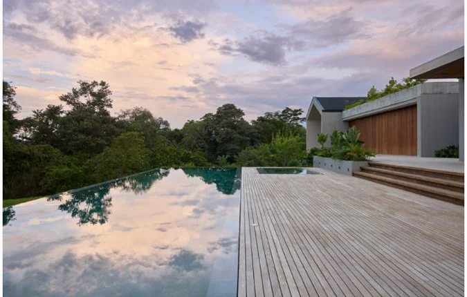 Piscina infinita reflejando el cielo del atardecer